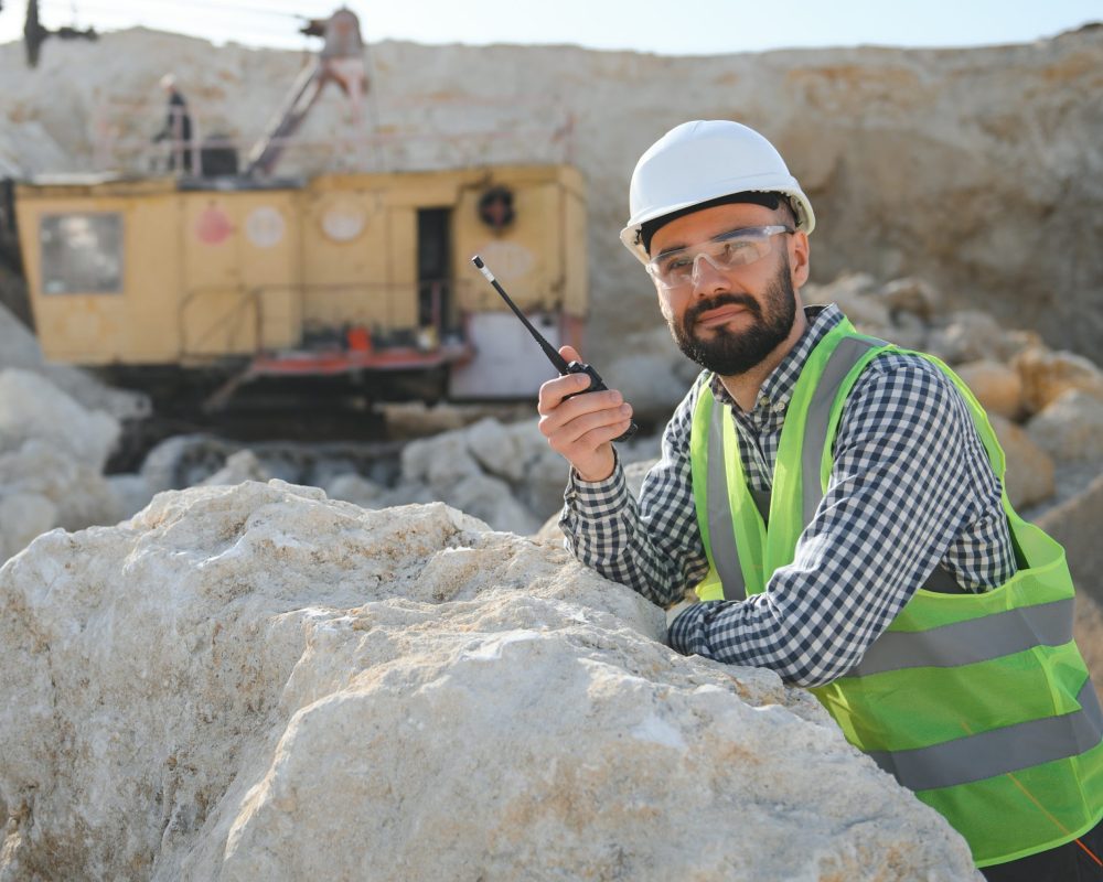 Extraction of stone. Male worker next to stone quarry. Engineer at construction site.